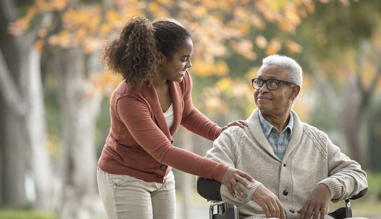 African American woman pushing father in wheelchair